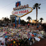 The “Welcome to Las Vegas” sign is surrounded by flowers and items, left after the October 1 mass shooting, in Las Vegas